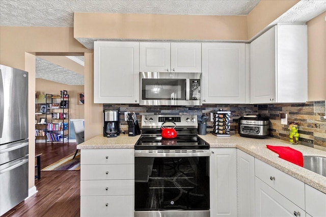 kitchen with stainless steel appliances, white cabinets, decorative backsplash, and dark wood-style floors