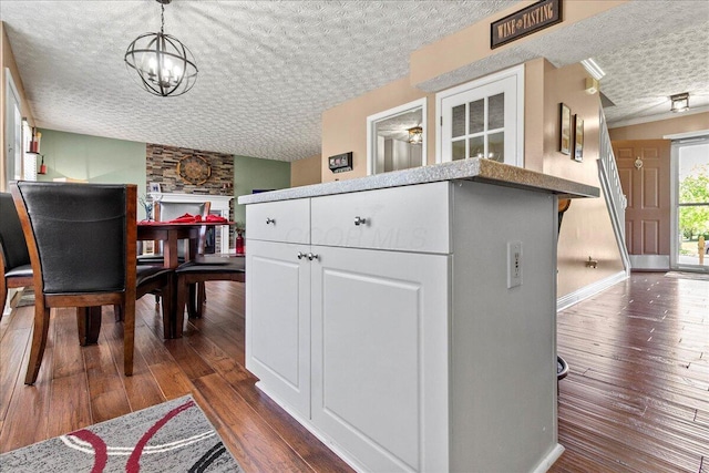 interior space with a notable chandelier, dark wood finished floors, white cabinets, and a textured ceiling