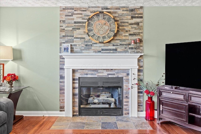 living area with baseboards, a fireplace, and wood finished floors