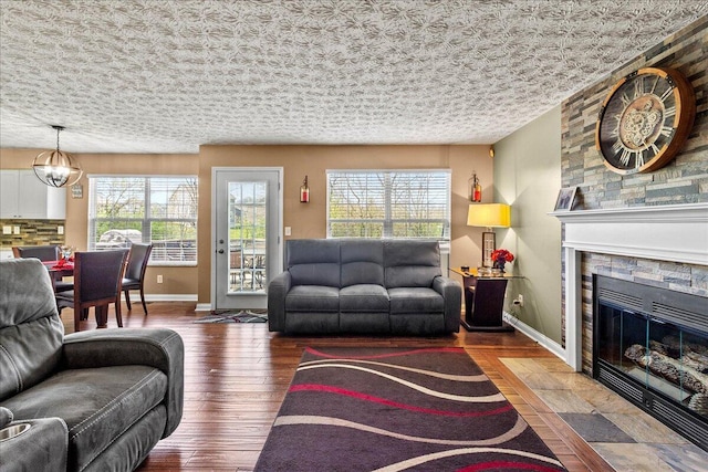 living room with wood finished floors, baseboards, and a stone fireplace