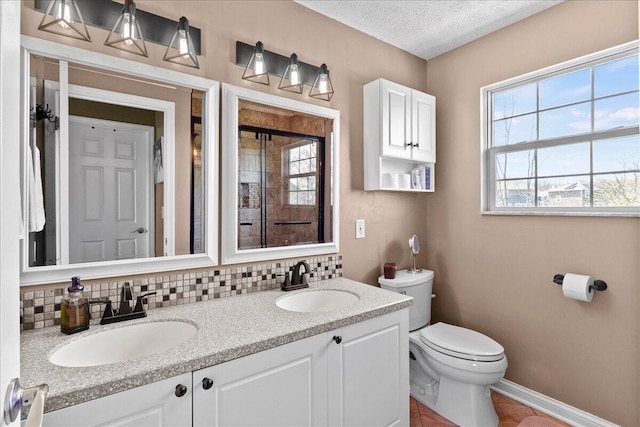 full bath featuring a sink, double vanity, toilet, and baseboards