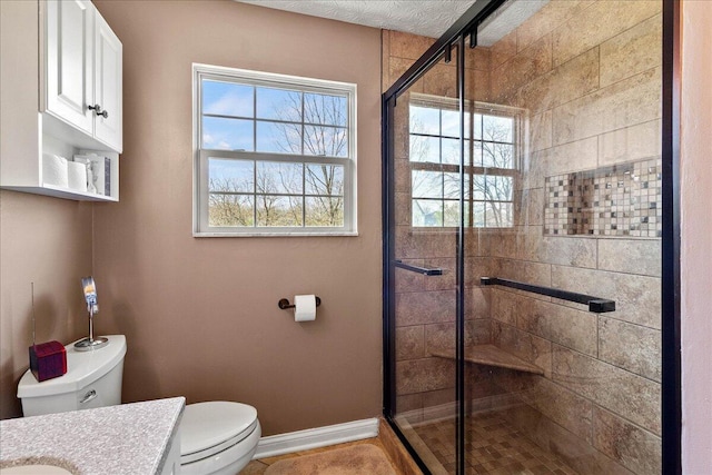 full bath with a stall shower, vanity, toilet, and baseboards