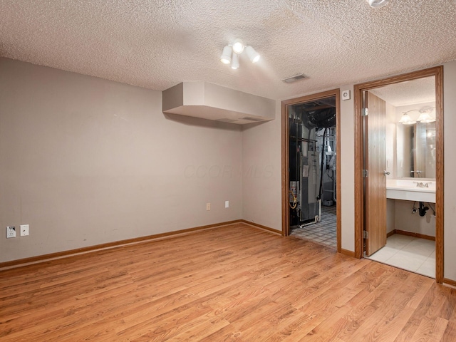 5690 Kilbury Ln Unit 120D, Hilliard, OH 43026 - unfurnished bedroom with light wood finished floors, a spacious closet, a textured ceiling, a closet, and ensuite bath