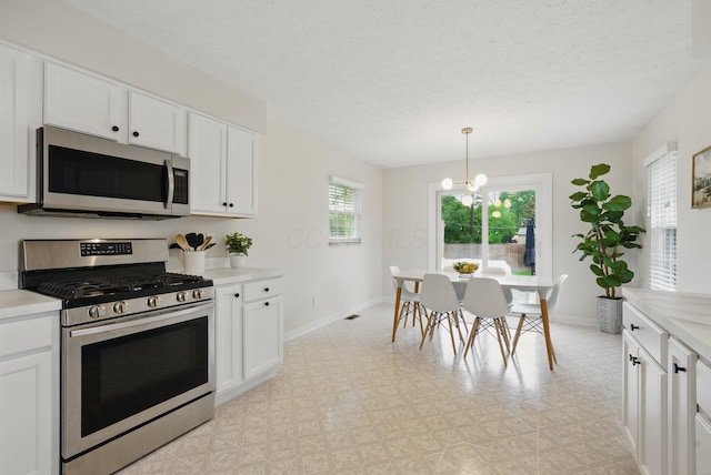 kitchen featuring stainless steel appliances, baseboards, white cabinetry, light countertops, and a textured ceiling