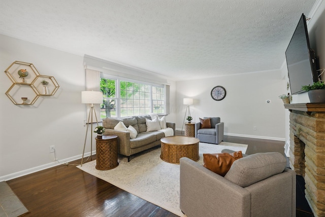 living room with a textured ceiling, dark wood-style floors, a stone fireplace, and baseboards