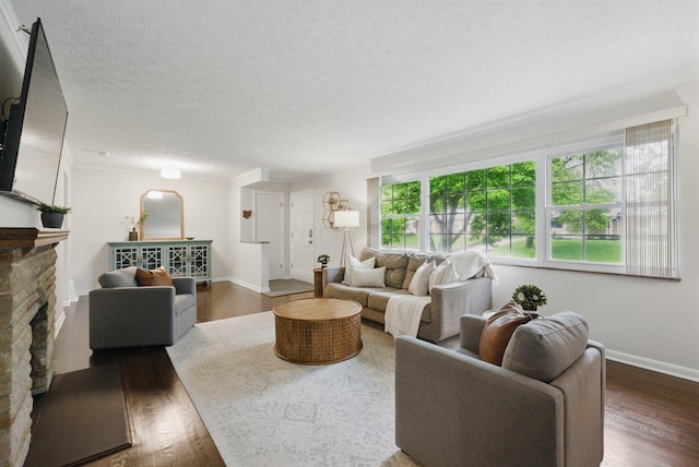 living room with dark wood finished floors, baseboards, a textured ceiling, and a stone fireplace