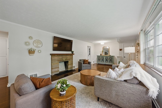 living area with wood finished floors, a fireplace, ornamental molding, and baseboards