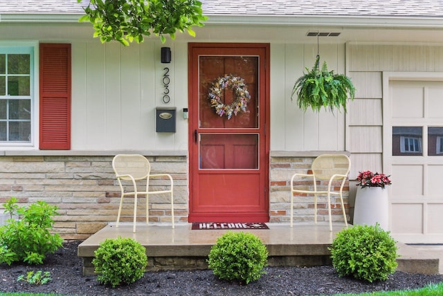 entrance to property with a shingled roof and stone siding