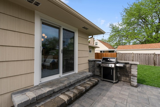 view of patio / terrace featuring fence, grilling area, and an outdoor kitchen