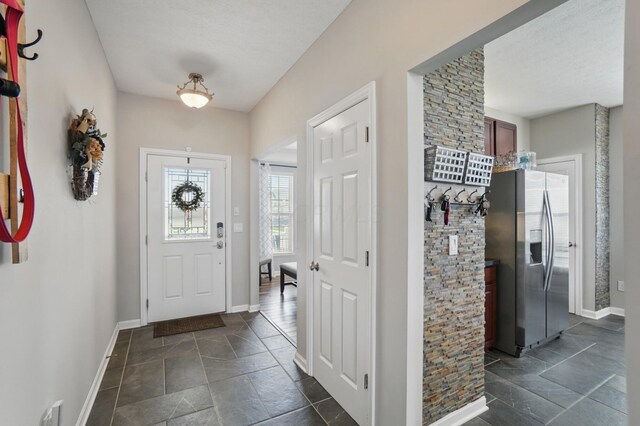 entryway with baseboards and stone tile flooring