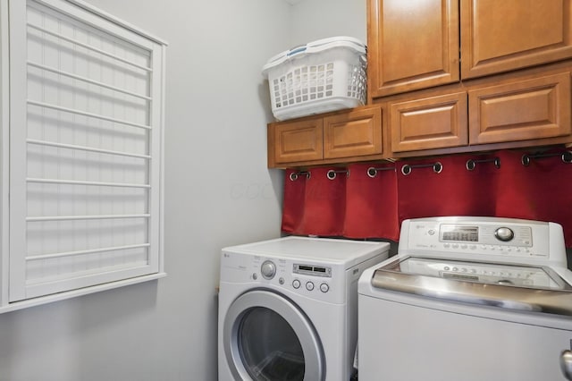 clothes washing area with washer and dryer and cabinet space