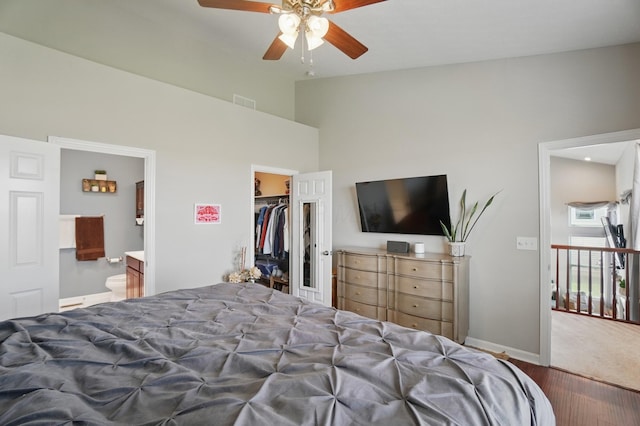 bedroom featuring wood finished floors, a closet, a spacious closet, baseboards, and visible vents