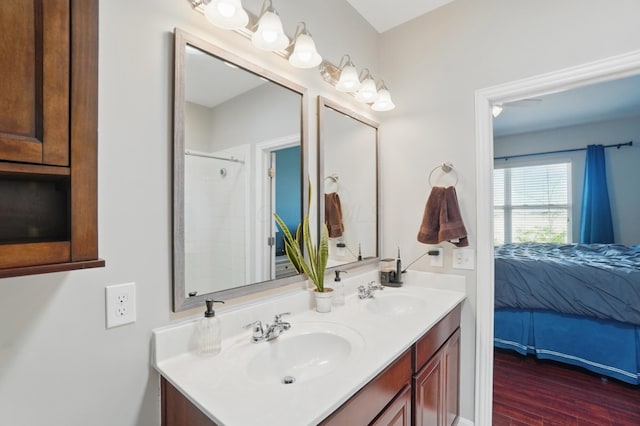 bathroom featuring walk in shower, wood finished floors, a sink, and double vanity