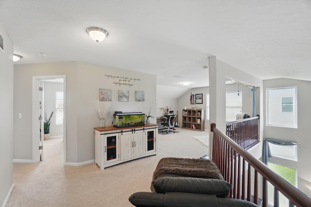 interior space featuring light carpet, lofted ceiling, and baseboards