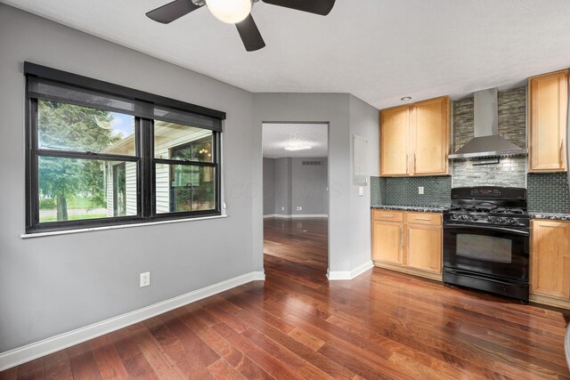kitchen with tasteful backsplash, black gas stove, ceiling fan, baseboards, and wall chimney exhaust hood