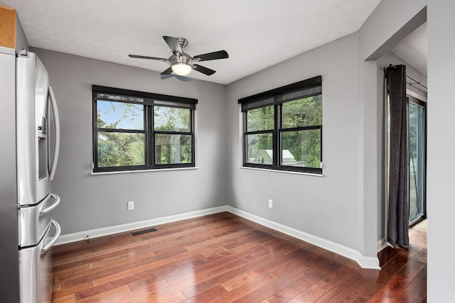 interior space featuring ceiling fan, visible vents, wood-type flooring, and baseboards