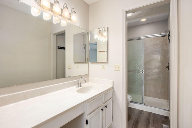 bathroom with a stall shower, toilet, wood finished floors, and vanity