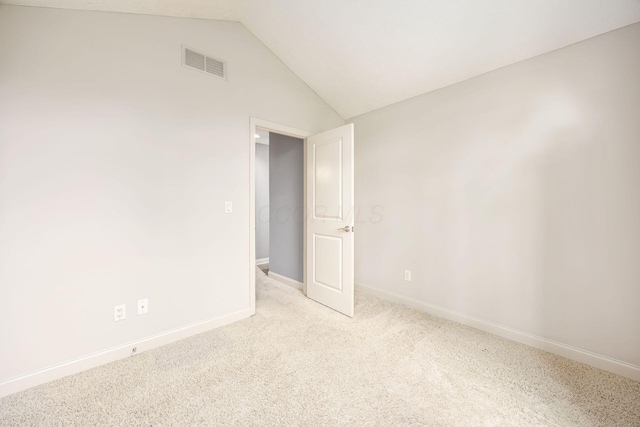 carpeted spare room featuring visible vents, vaulted ceiling, and baseboards