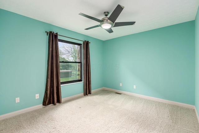empty room with a ceiling fan, light carpet, and baseboards