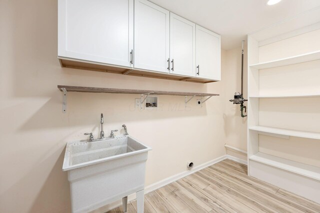 clothes washing area with washer hookup, electric dryer hookup, baseboards, light wood-type flooring, and cabinet space