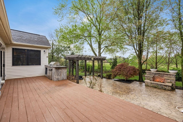 wooden deck with exterior kitchen, area for grilling, a patio area, and a pergola