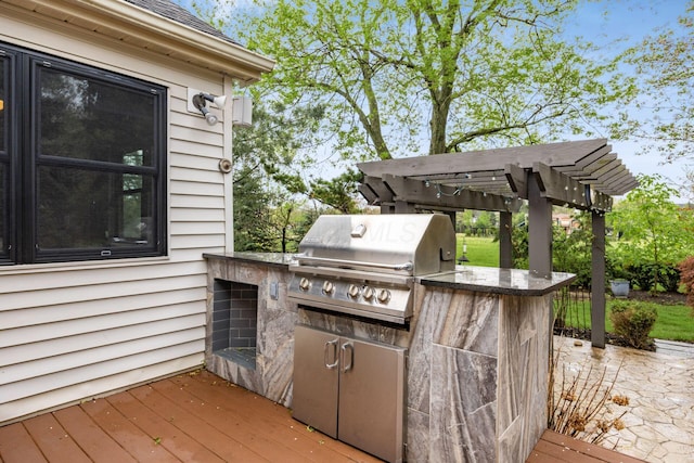 view of patio / terrace featuring area for grilling, a pergola, a wooden deck, and an outdoor kitchen