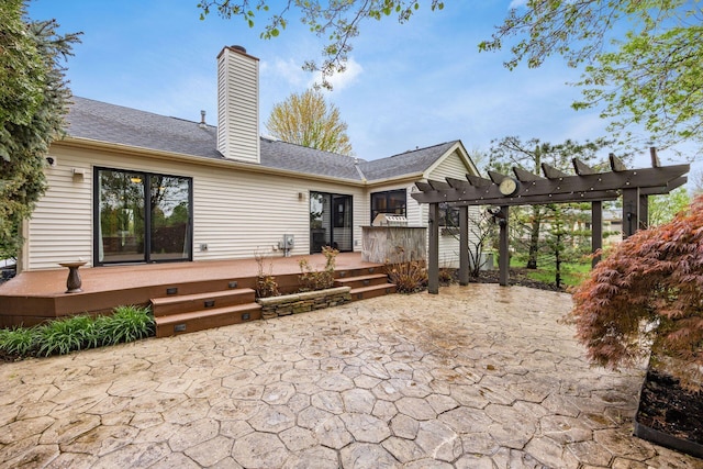 back of property with a patio, a wooden deck, a pergola, a shingled roof, and a chimney
