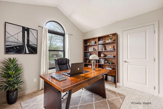office area featuring lofted ceiling, baseboards, and light carpet