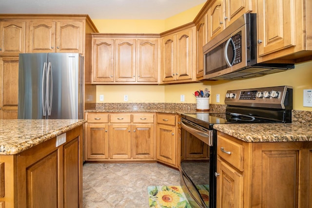 kitchen with light stone counters, appliances with stainless steel finishes, and brown cabinets