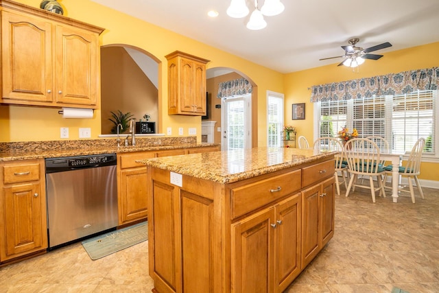 kitchen featuring light stone countertops, dishwasher, arched walkways, ceiling fan with notable chandelier, and a center island