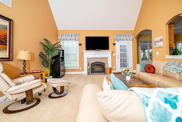 carpeted living area with high vaulted ceiling, baseboards, a tile fireplace, and visible vents
