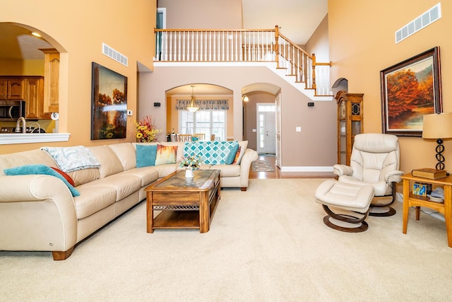 living area featuring visible vents, arched walkways, and a towering ceiling