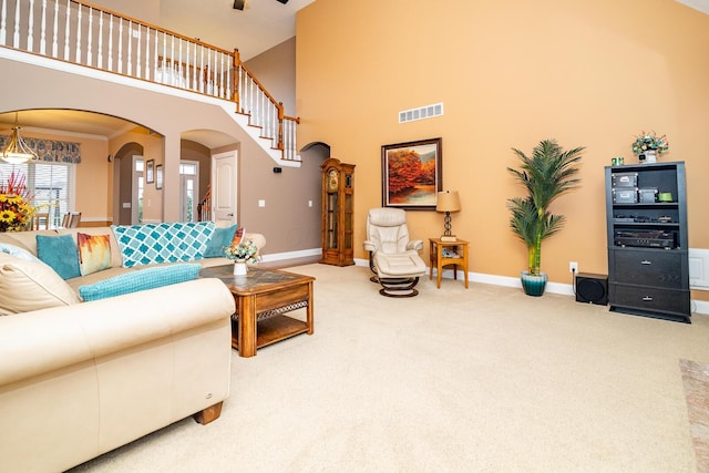 living area featuring visible vents, baseboards, a high ceiling, arched walkways, and carpet