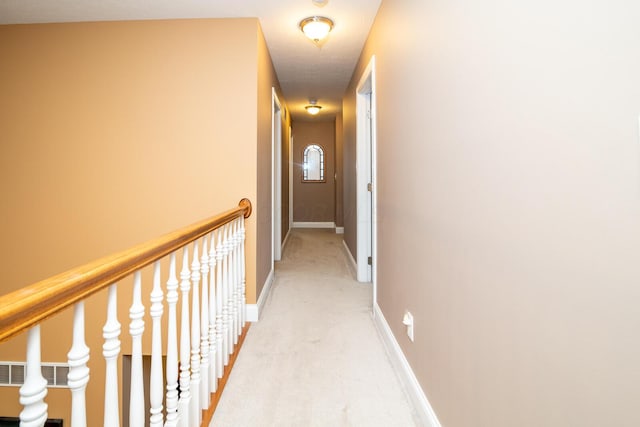 hall with baseboards and light colored carpet