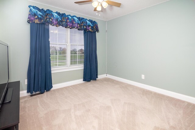 empty room with baseboards, ceiling fan, and carpet flooring