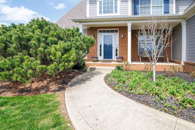 property entrance featuring covered porch and brick siding