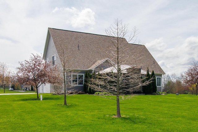 exterior space featuring a lawn, a shingled roof, an attached garage, and driveway