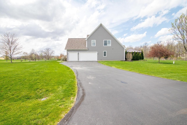 view of side of home featuring a lawn, a shingled roof, and aphalt driveway