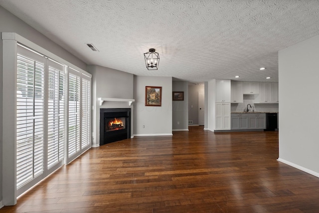 6709 Axtel Dr Unit 5A, Canal Winchester, OH 43110 - unfurnished living room with recessed lighting, a textured ceiling, a glass covered fireplace, a sink, and dark wood-style floors