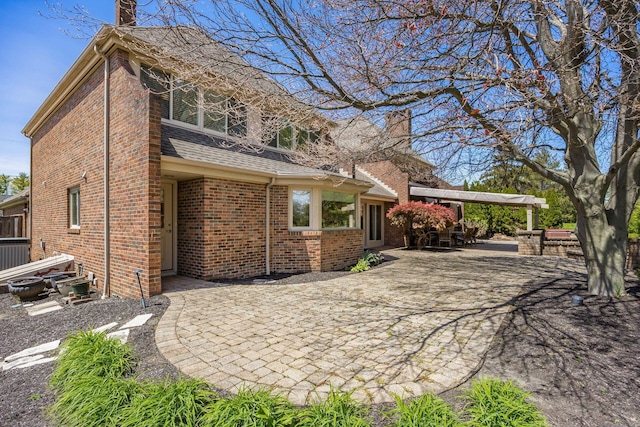 rear view of house with brick siding, central AC unit, a patio area, and a chimney