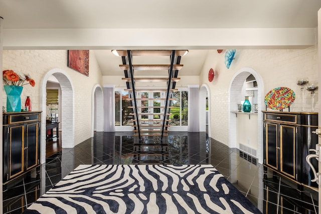interior space featuring visible vents, arched walkways, lofted ceiling, and brick wall