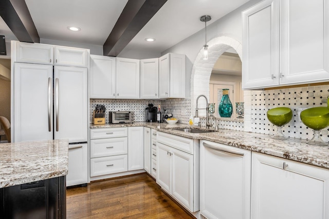 kitchen featuring decorative backsplash, built in fridge, a sink, white cabinets, and dark wood-style floors