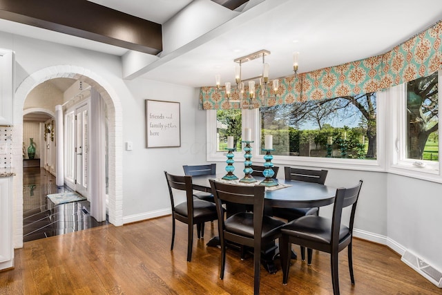 dining area featuring baseboards, arched walkways, wood finished floors, and visible vents