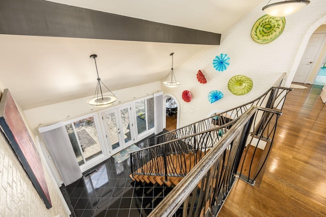 staircase featuring arched walkways, french doors, wood finished floors, and lofted ceiling