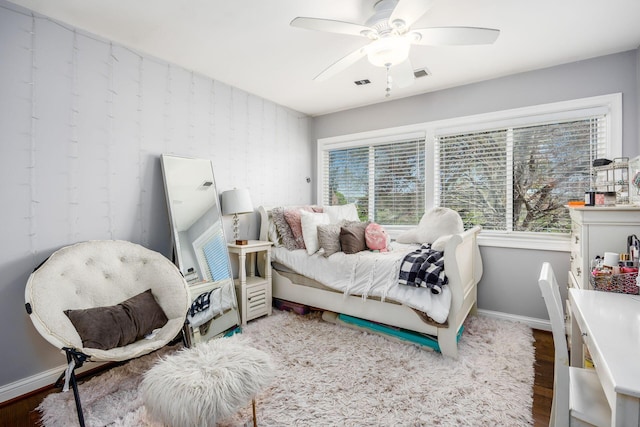 bedroom with baseboards, ceiling fan, wood finished floors, and visible vents