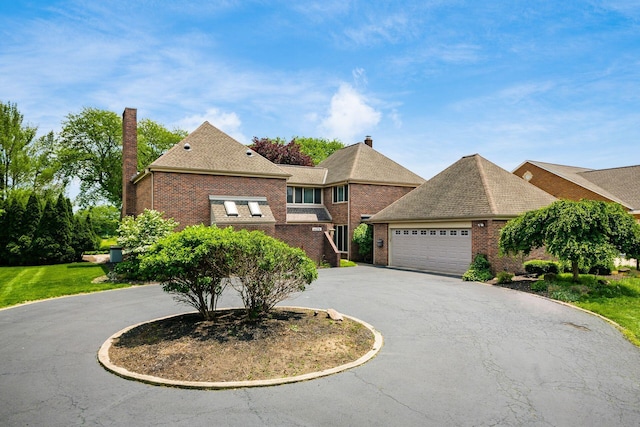 4070 Lyon Dr, Upper Arlington, OH 43220 - view of front of house with curved driveway, brick siding, a chimney, a garage, and roof with shingles