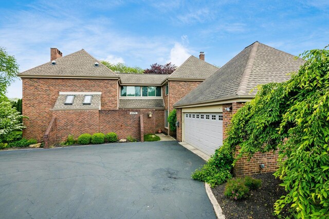 4070 Lyon Dr, Upper Arlington, OH 43220 - view of front of home with brick siding, asphalt driveway, a chimney, and a garage