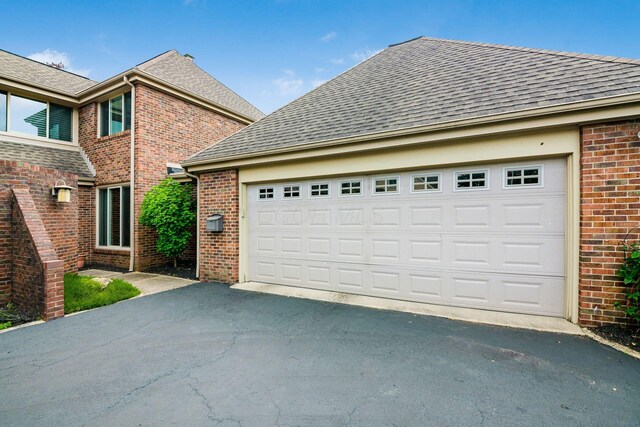 4070 Lyon Dr, Upper Arlington, OH 43220 - view of property exterior featuring brick siding, driveway, a shingled roof, and an attached garage