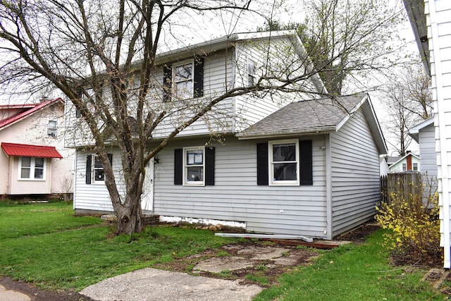 view of front of house with a shingled roof, a front yard, and fence