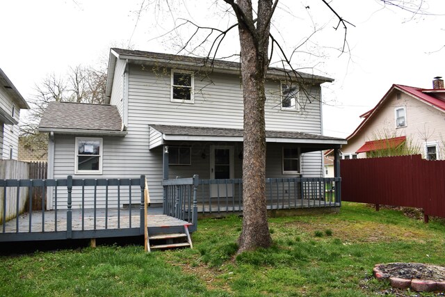 rear view of property with a wooden deck, a yard, a shingled roof, and fence